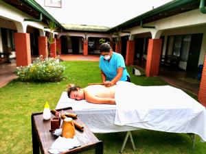 a woman laying on a towel in the grass with a man at Hotel Wagelia Turrialba in Turrialba