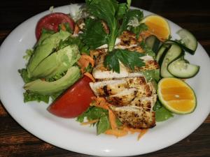 a plate of food with chicken and a salad at Hotel Wagelia Turrialba in Turrialba