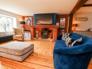 a living room with a blue couch and a fireplace at Noah's Barn in Poulton le Fylde