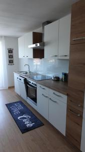 een keuken met witte kasten en een keukenkleed op de vloer bij JOE's Appartement in Ebbs