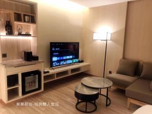 sala de estar con TV, sofá y mesa en 菓菓輕旅, en Puli