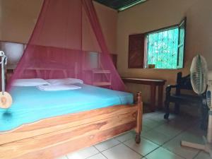 1 dormitorio con cama de madera y dosel rojo en Hostal Así es mi Tierra en Balgue