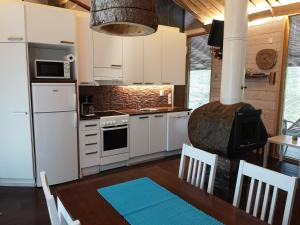 a kitchen with a stove and a table with chairs at Loma-asunto Ahven, Kalajärvi, Maatilamatkailu Ilomäen mökit in Seinäjoki