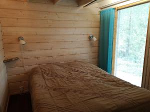 uma cama num quarto de madeira com uma janela em Loma-asunto Ahven, Kalajärvi, Maatilamatkailu Ilomäen mökit em Seinäjoki