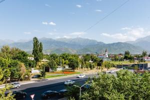 a street with cars driving down a road with mountains at Книжный Город in Almaty