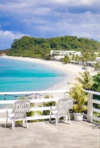 Duas cadeiras brancas sentadas numa varanda com vista para uma praia em Playa Blanca Beach Resort em Puerto Galera