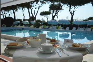 a table with food and drinks next to a swimming pool at Hotel Bauer & Sporting in Lido di Jesolo