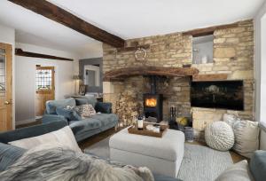a living room with couches and a stone fireplace at Corner Cottage in Adlestrop