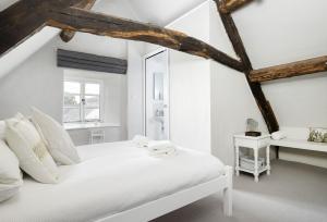 a white bedroom with a white bed and a window at Corner Cottage in Adlestrop