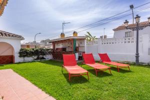a group of red chairs sitting on the grass in a yard at Villa espectacular in Rincón de la Victoria
