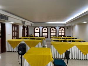 pokój ze stołami i krzesłami z żółtymi narzutami w obiekcie Hotel Faranda Bolivar Cucuta, a member of Radisson Individuals w mieście Cúcuta