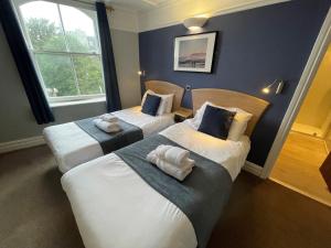 2 camas en una habitación con paredes azules en The George Hotel, en Whitby