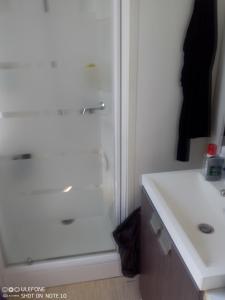 uma casa de banho com um chuveiro e um lavatório branco em mobil home 001 em Agde