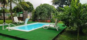 a pool in a yard with two chairs and a table at Dharma Casa Holistica, Vivero, Yoga y Retiros in Chame