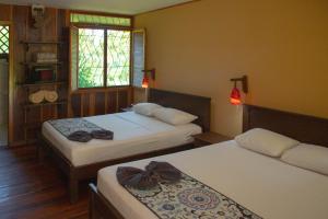 1 dormitorio con 2 camas y ventana en Laguna Lodge en Tortuguero