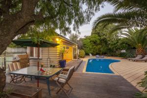 a patio with a table and chairs and a pool at Kapiti Getaway - Paraparaumu Beach Rental in Paraparaumu Beach