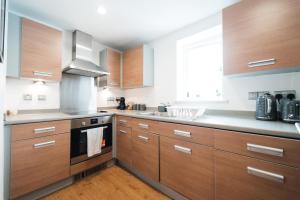 a large kitchen with wooden cabinets and a window at Lovely 2 bedroom flat next to Victoria Park in London