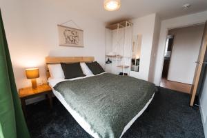 a bedroom with a large bed with a green blanket at Lovely 2 bedroom flat next to Victoria Park in London