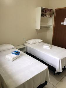 2 Betten in einem Hotelzimmer mit weißer Bettwäsche in der Unterkunft Stela Maris in Guaratuba