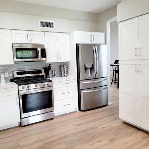 una cocina con armarios blancos y electrodomésticos de acero inoxidable en PEACEFUL lakeside home, minutes from Downtown Gilbert, en Gilbert