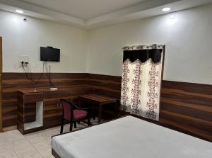 a room with a bed and a desk and a tv at HOTEL THILAK in Tuticorin