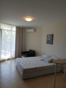 a bedroom with a bed and a chair and a window at Midia Grand Resort in Aheloy