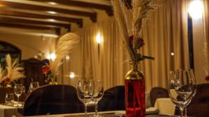 a vase with flowers in it on a table with glasses at Hotel Villa Letan in Fažana