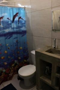a bathroom with a toilet and a shower curtain with dolphins at Casa Recanto das Mangueiras Japaratinga - Alagoas in Japaratinga