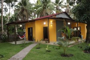 a small yellow house with a garden at Casa Recanto das Mangueiras Japaratinga - Alagoas in Japaratinga