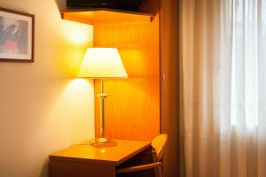 una lámpara sentada en un escritorio junto a una ventana en Hostal Restaurant Roma, en Cubells