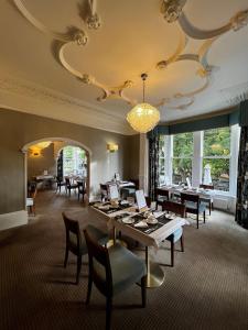 uma sala de jantar com mesas e cadeiras e um lustre em Ascot House em Harrogate