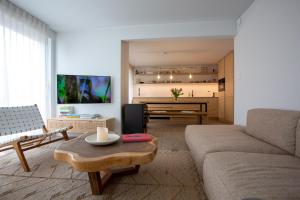 a living room with a couch and a table at 'A little white house with a tree by the sea' with beach cabin by BLOSS in Nieuwpoort