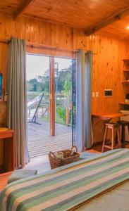 Schlafzimmer mit einem Bett und einem großen Fenster mit einer Terrasse in der Unterkunft Cabañas Alba in Nueva Italia