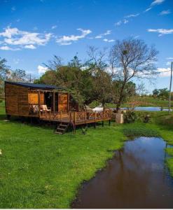 eine Holzhütte mit einer Brücke an einem Fluss in der Unterkunft Cabañas Alba in Nueva Italia