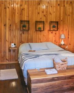 ein Schlafzimmer mit einem Bett und einer Holzwand in der Unterkunft Cabañas Alba in Nueva Italia