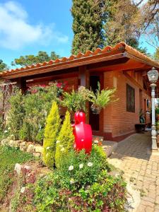 a house with a red fire hydrant in a garden at Pousada Anecuém in Monte Verde