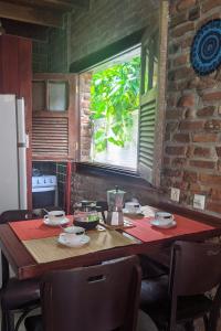 a kitchen with a wooden table with chairs and a window at Chalés na Hora in Olinda