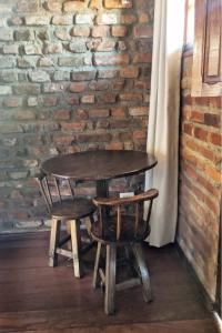a wooden table and two chairs next to a brick wall at Chalés na Hora in Olinda