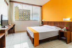 a bedroom with a bed and a desk and a window at Alice Vitoria Hotel Arte by Nobile in Vitória