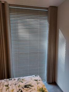 a bedroom with a large window with blinds and a bed at Geniet van alle comfort tussen Ieper en Heuvelland in Ypres