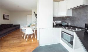 a kitchen with white cabinets and a table and a couch at Fantastic 3 bedrooms flat in Euston Zone 1 in London