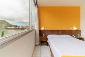 a bedroom with a bed and a large window at Alice Vitoria Hotel By Nobile in Vitória