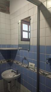 een blauwe en witte badkamer met een wastafel en een spiegel bij Chalés na Hora in Olinda