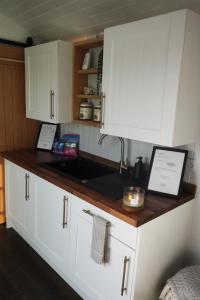 una cocina con armarios blancos y fregadero en Four Acres Farm Shepherds Huts en Donaghadee