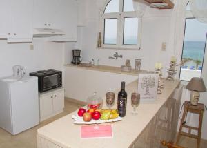 a kitchen with a counter with fruits and wine bottles at white house by the sea in Kokkíni Khánion