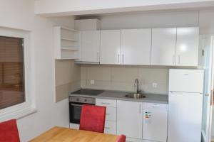 a kitchen with white cabinets and a table and red chairs at Soba KONAK 4 in Jajce +2 photos