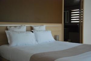 a white bed with white pillows in a bedroom at Hôtel Le Barry, Toulouse Nord in Gratentour