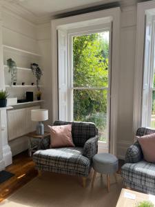 a living room with two chairs and a window at Elegant Bloomsbury Apartment in Tunbridge Wells in Royal Tunbridge Wells