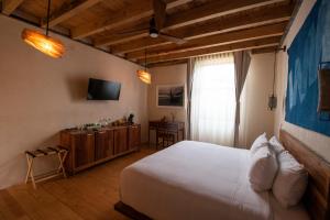 a bedroom with a large white bed and a television at Hotel Los Amantes in Oaxaca City