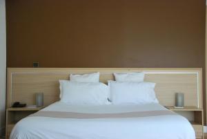 a large bed with white sheets and pillows at Hôtel Le Barry, Toulouse Nord in Gratentour
